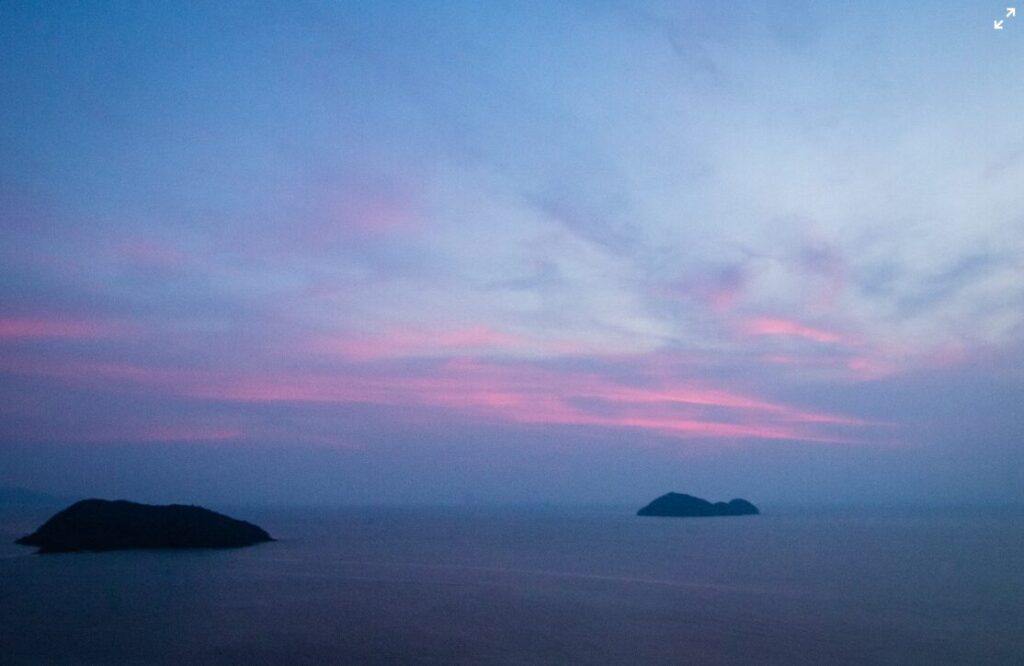 Malowniczy zachód słońca nad Koh Phayam z widokiem na morze i wyspy w oddali.