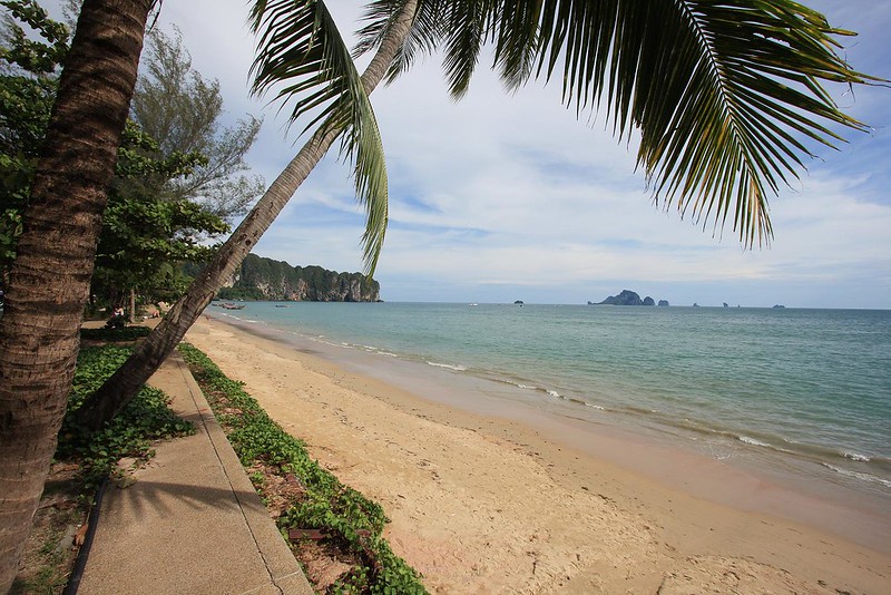 Plaża Noppharat Thara w Tajlandii – piaszczysta linia brzegowa z palmami, błękitnym niebem i spokojnym morzem.