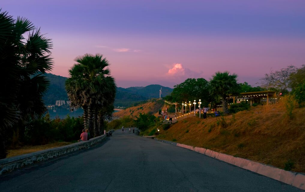 Punkt widokowy Windmill Viewpoint na Phuket o zachodzie słońca, z malowniczą drogą prowadzącą w stronę wiatraka.