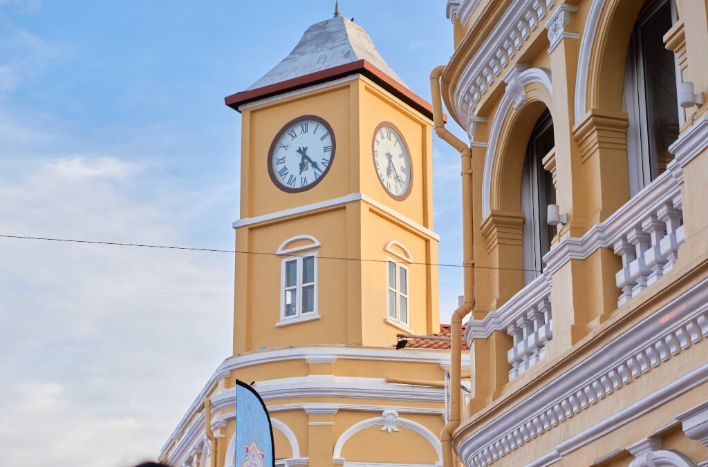 Zabytkowy budynek z zegarem w Phuket Old Town, w stylu sino-portugalskim, na tle błękitnego nieba.