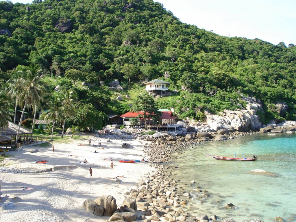 Zatoka Ao Leuk na Koh Tao z białym piaskiem, turkusową wodą i skałami w tle