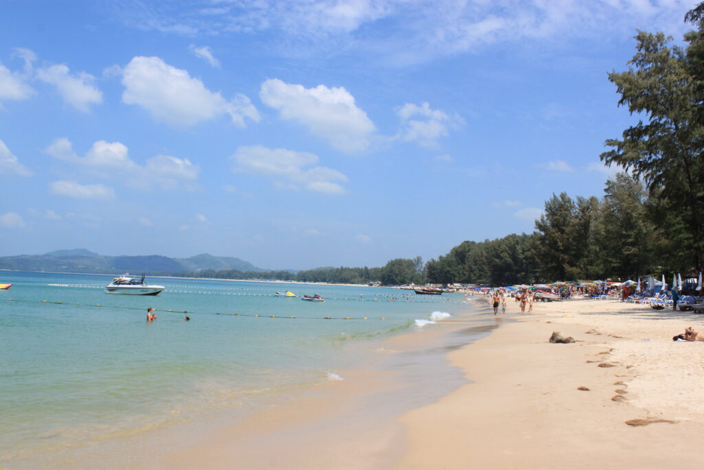 Plaża Bang Tao na Phuket z jasnym piaskiem, palmami i spokojnym morzem w tle.