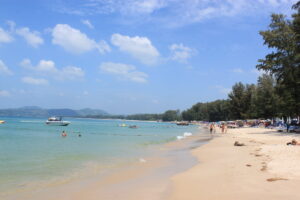 Plaża Bang Tao na Phuket z jasnym piaskiem, palmami i spokojnym morzem w tle.