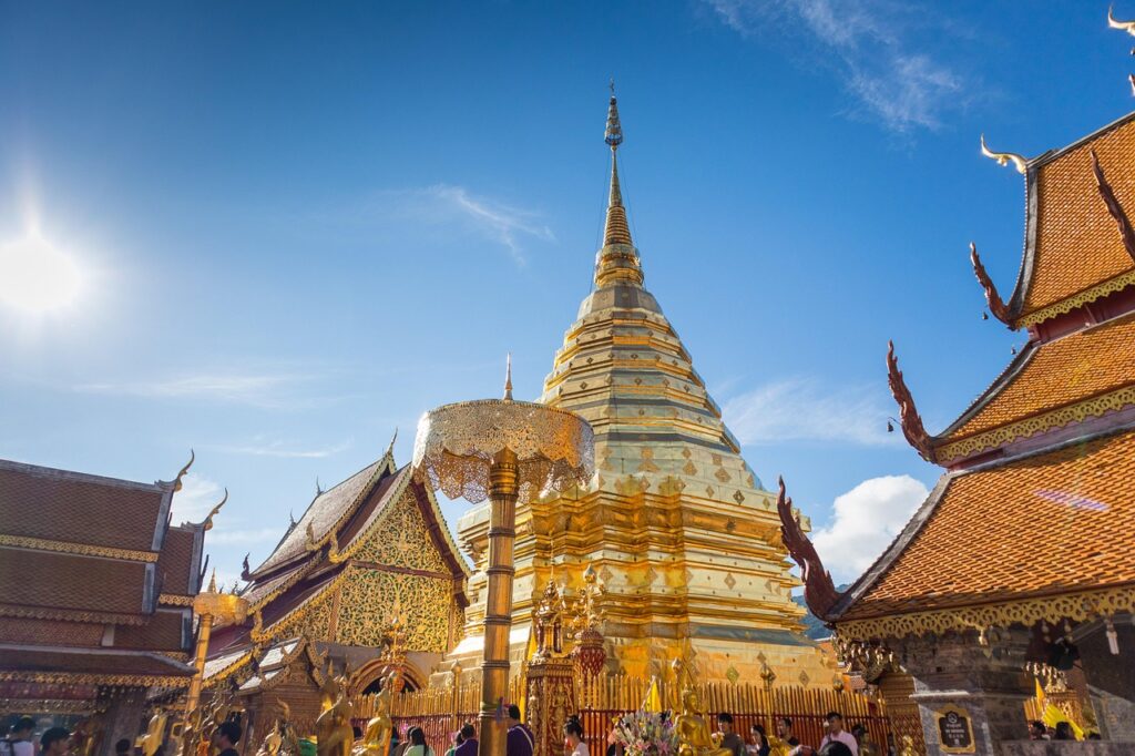 Złota stupa świątyni Wat Phra That Doi Suthep w Chiang Mai, lśniąca w promieniach słońca na tle błękitnego nieba.