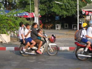 Grupa osób na skuterach w Tajlandii, popularnym środku transportu w kraju.