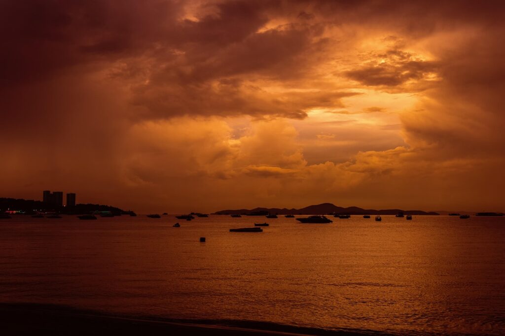 Zachód słońca nad Zatoką Tajlandzką widziany z Pattayi – ciemne sylwetki łodzi na tle pomarańczowego nieba.