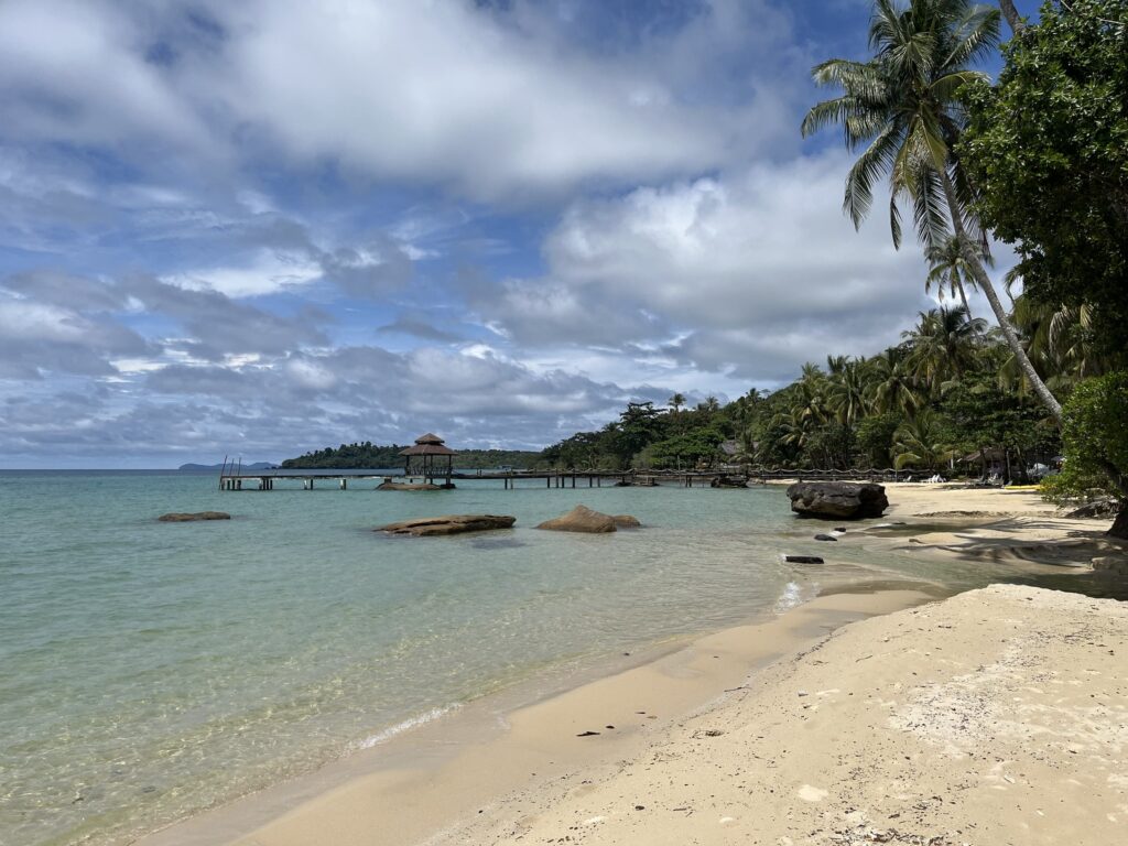 Tropikalna plaża na wyspie Koh Kood z białym piaskiem, turkusową wodą i palmami pod błękitnym niebem.