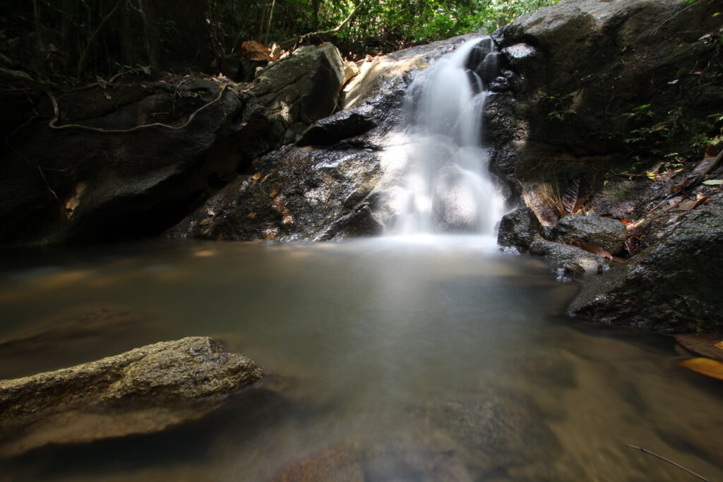 Wodospad Kathu na Phuket – kaskada wody spływająca po kamieniach w otoczeniu tropikalnej roślinności.