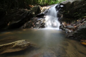 Wodospad Kathu na Phuket – kaskada wody spływająca po kamieniach w otoczeniu tropikalnej roślinności.